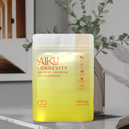 Yellow and white package of Aiku Longevity mushroom fusion capsules on a surface with a plant in the background.